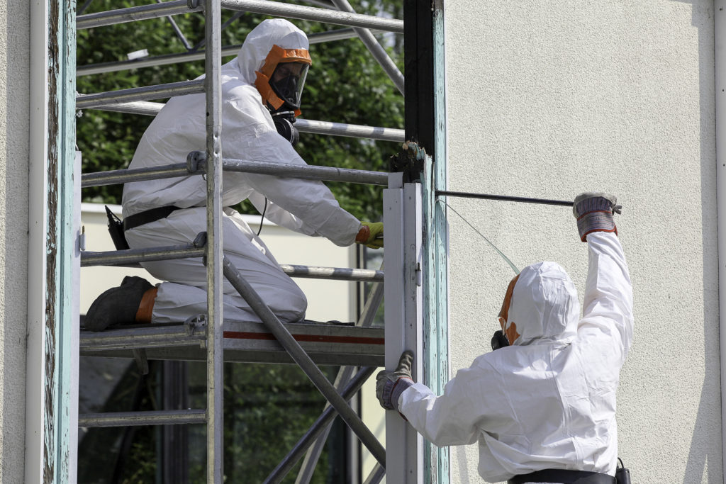 Professional cleaners decontaminating a window outside.