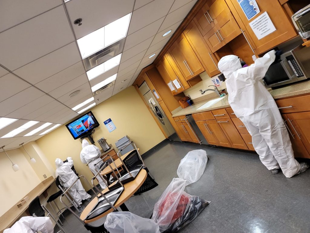 Professionals decontaminating an office cafeteria room.