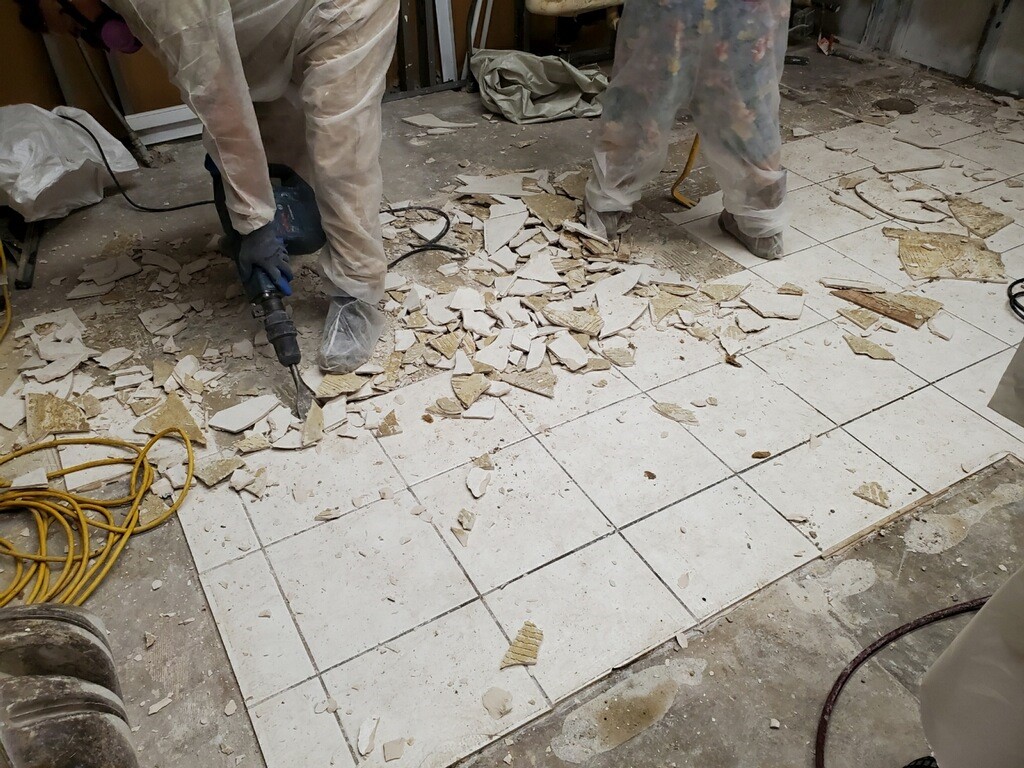 The construction worker removing the tiles.